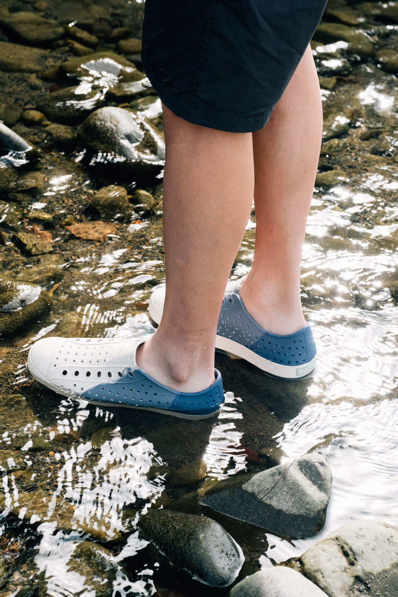 nativeの靴を履いた男性が川の浅瀬に立つイメージ