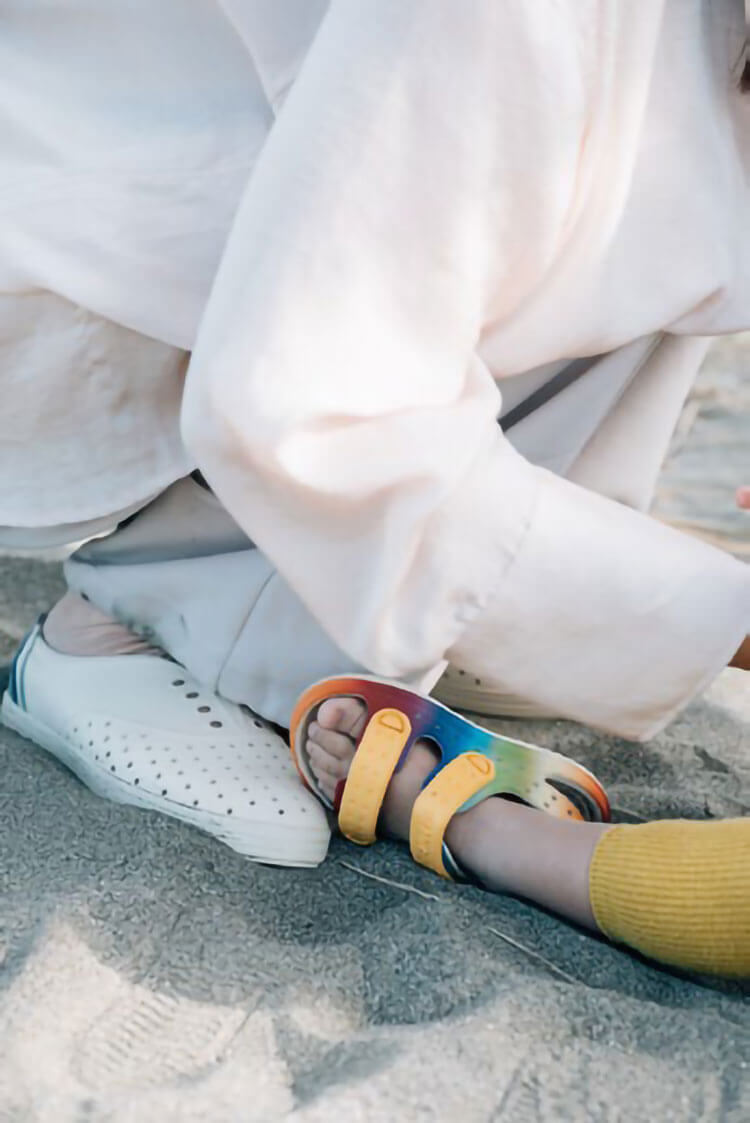 nativeの靴を履いた女性と子どもが砂場で座っているイメージ