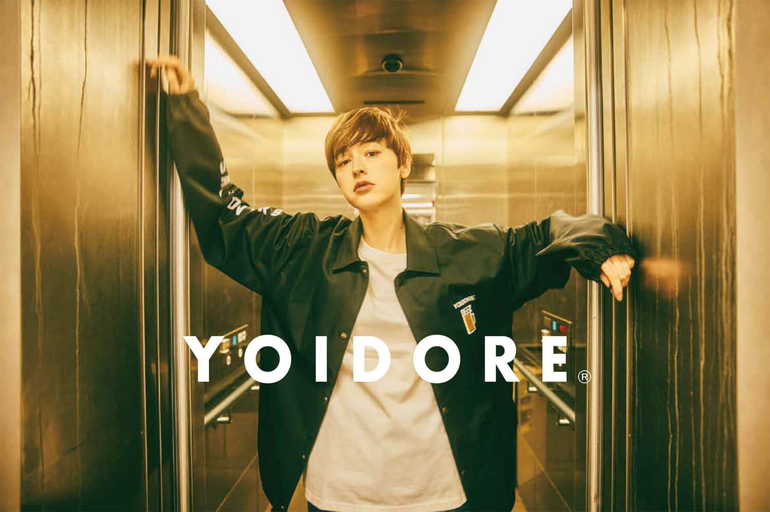 YOIDOREのジャンバーを着た若い女性がエレベーターから出てくるイメージ画像