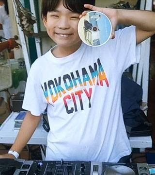 YOKOHAMA CITYと書かれた白いTシャツを着て左手にCDを持ちポーズをとるKONOSUKEさん
